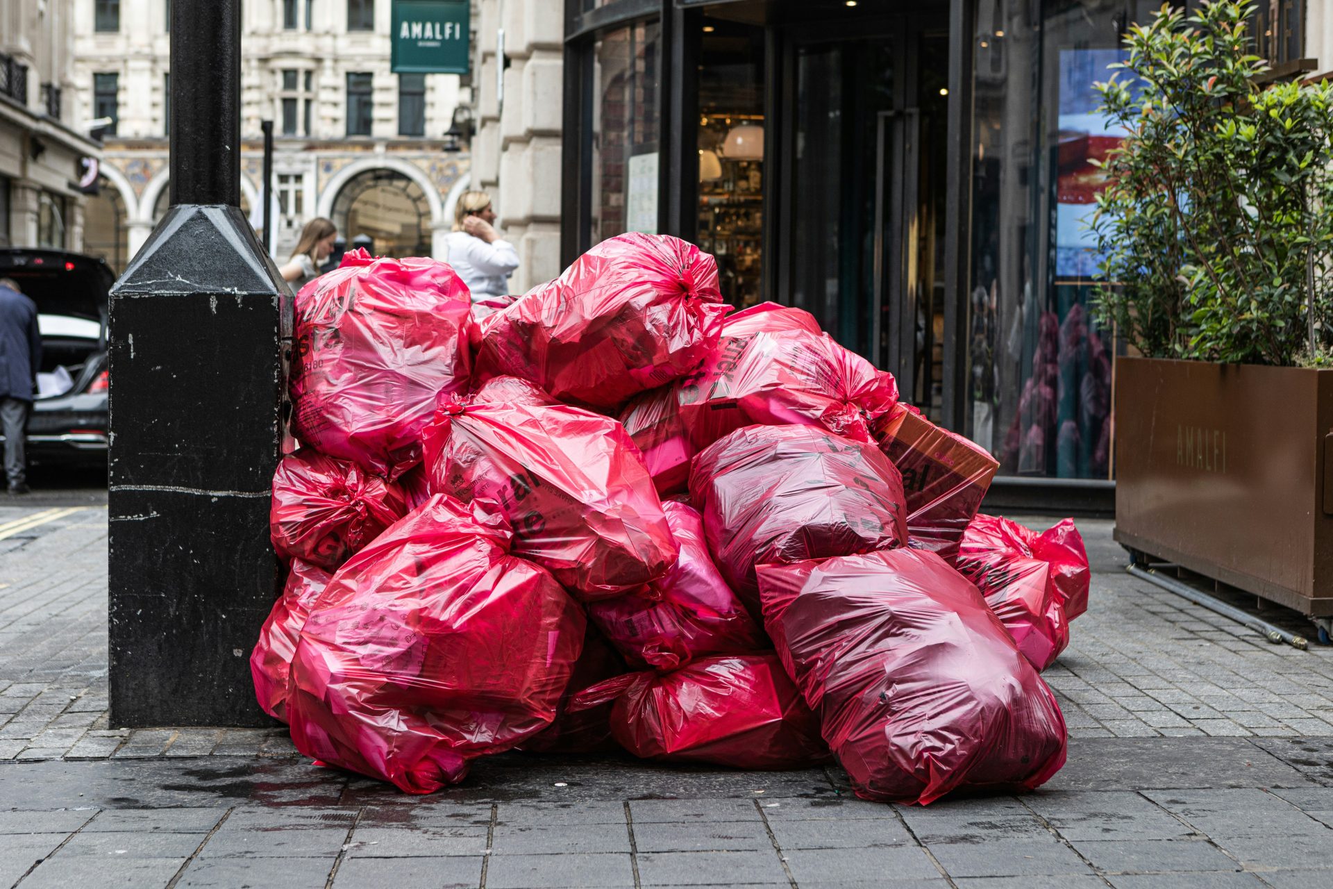 a pile of red bags sitting on the side of a street