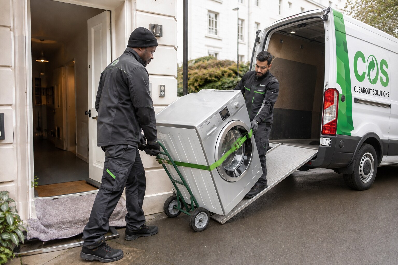 Workers moving a washing machine safely with an appliance trolley.